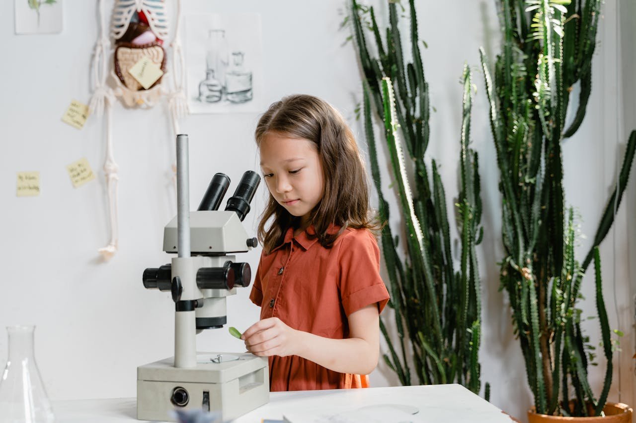 Curious girl using microscope for a science project in a classroom setting.