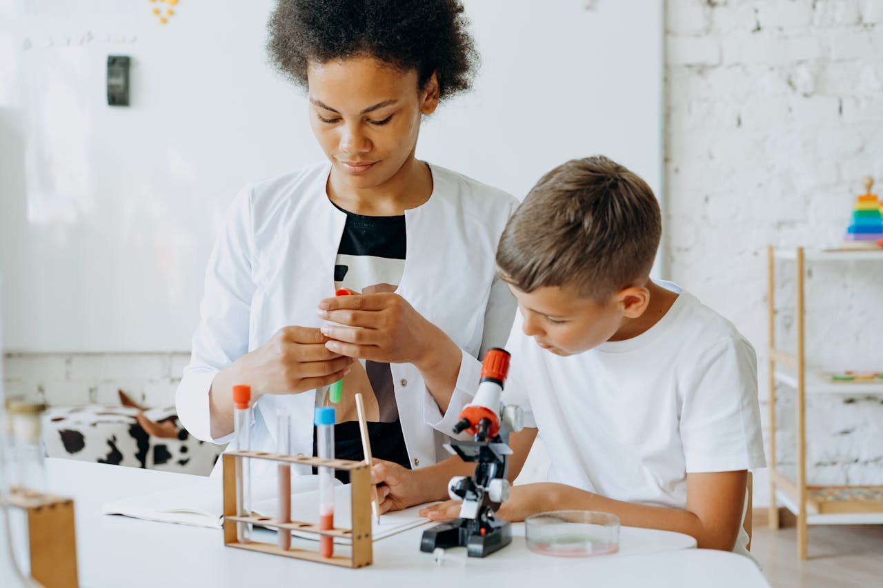 A teacher guides a student during a science experiment in a classroom setting.